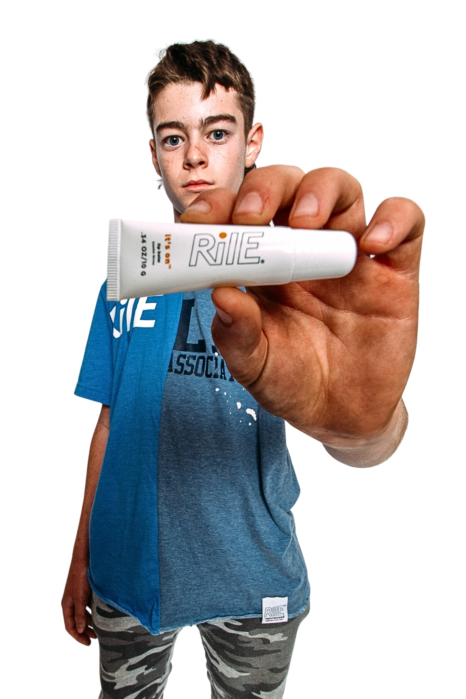 A young teen or tween holding a tube of the Rile lip balm.